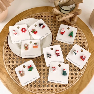 Flat lay of festive Christmas stud earring set with Santa, elk, and snowman on a white plate