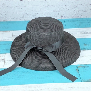 Close-up of elegant black wide-brim straw hat featuring a chic satin ribbon bow detail