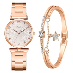 Close-up of rose gold watch set with star charm bracelet and Arabic numeral dial
