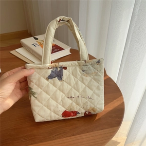 Close-up of quilted cotton phone pouch with cartoon rabbit patterns on a warm wooden desk