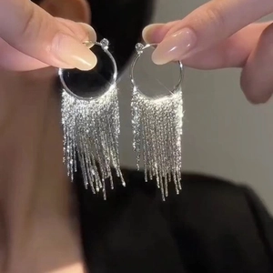 Detailed view of silver geometric C-hoop earrings featuring sparkling glitter tassels