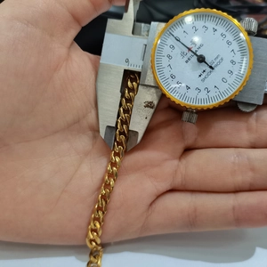 Close-up of golden Cuban chain link width measurement using digital calipers tool