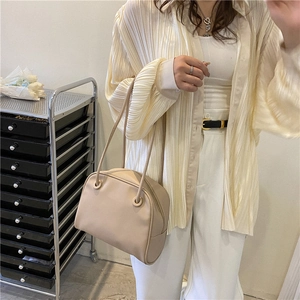Minimalist cream white shoulder tote bag worn by model in a stylish indoor setting