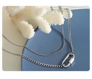Detail einer silbernen zweilagigen Kette mit U-förmigem Anhänger und Karabinerverschluss