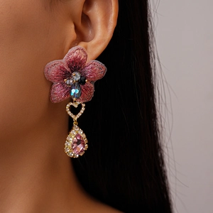 Gros plan de boucle d'oreille fleur brodée rose avec larme en cristal et strass