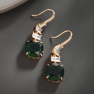 Macro detail of gold vintage earrings with emerald green gemstones and white diamonds