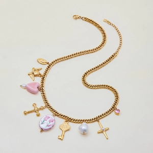 Close-up of gold snake chain necklace with ceramic heart and angel coin pendants