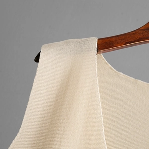 Detailed macro view of the cream knitted fabric shoulder texture and fine stitching