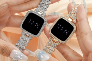 Close-up of gold and silver square LED watches with diamonds on pink silk background