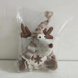 Close-up of a knitted reindeer plush ornament with a hat and scarf in a clear bag