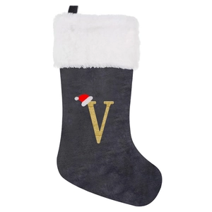 Close-up of a grey velvet Christmas stocking featuring a golden letter V and white faux fur trim