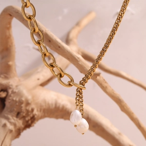 Detail of 18K gold plated layered chain necklace featuring white baroque pearls on wood