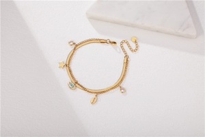 Detail of gold layered stainless steel bracelet with evil eye, star and shell charms