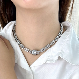 Close-up of silver-tone H-link chain necklace with square crystal pendant on model