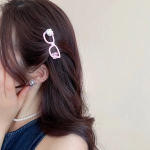 Detail of pink glasses-shaped hair clip with cartoon cat motif on brown hair