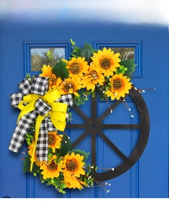 Detail of sunflower wreath with black and white bows on a rustic wooden wheel