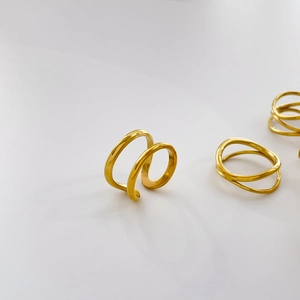 Close-up of polished gold double-layered open ring with minimalist wavy intertwining lines