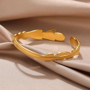 Detail of golden feather open cuff bracelet with dot embossing on champagne satin