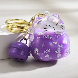 Close-up of purple Maneki Neko keychain with glitter stars and gold metal ring