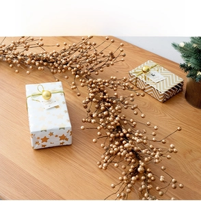 Detailed view of artificial golden berry vine on a wooden table with Christmas decor