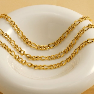 Polished gold titanium steel Figaro chain necklace displayed in a white ceramic dish