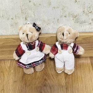 Dettaglio di ciondoli orsetto di peluche con abiti a quadri rossi e materiali morbidi