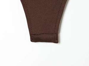 Detailed macro view of dark brown nylon bodysuit showing reinforced double-stitched hem