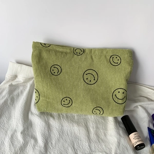 Macro detail of green corduroy fabric showing the soft texture and black smiley face prints