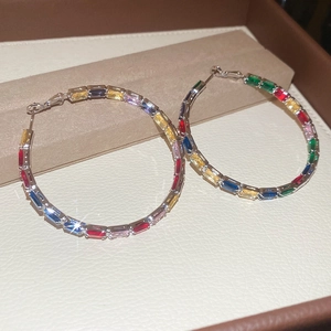 Macro shot of silver hoop earrings featuring colorful rectangular cut cubic zirconia stones