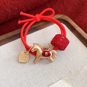 Détail de l'élastique à cheveux rouge avec pendentif poney doré et cube en strass rouge