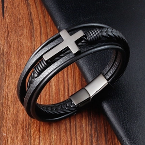 Detailed macro view of black braided leather multi-layer bracelet with metal cross and magnetic clasp