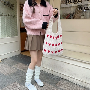 Detailed knit texture of white tote bag with red heart pattern in street style scene
