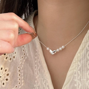 Close-up of a 925 sterling silver heart pearl necklace worn on a woman neck