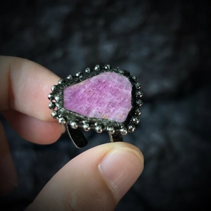 Dettaglio anello vintage regolabile con rubino grezzo su sfondo di roccia nera opaca