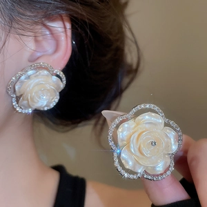 Close-up of elegant pearl resin rose earrings with sparkling rhinestone frame