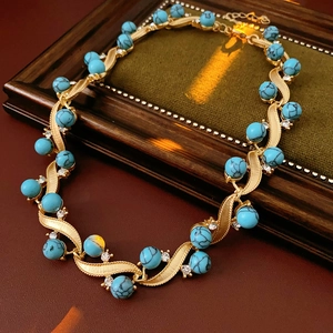Macro detail of vintage necklace featuring turquoise beads on gold wavy leaf pendant