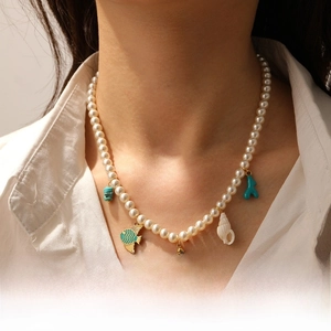Detail of ocean theme pearl necklace featuring tropical fish, sea turtle and coral charms