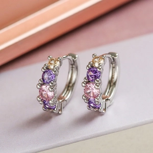 Orecchini minimalisti in argento con zirconi viola rosa e champagne su sfondo morbido