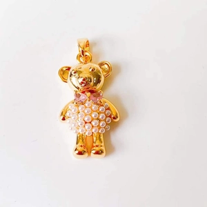 Detail of a gold bear pendant with white pearl body and pink gemstone bowknot