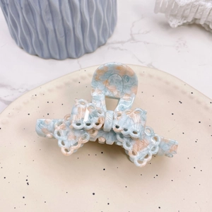 Detail of blue and pink marble acetate hair claw clip with lace bow cut-out design