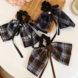 Detail view of plaid bow hair ties with handmade metal charms and elegant long ribbons
