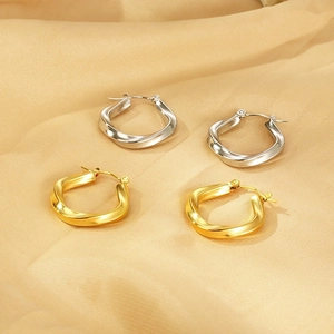Twisted square titanium steel earrings in gold and silver finish on silk fabric