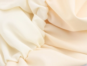 Close-up of soft beige fabric with subtle sheen and elegant drapery detail