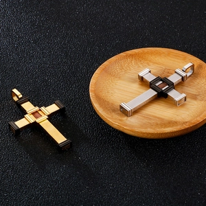 Close-up of gold and silver stainless steel cross pendants on a dark textured surface