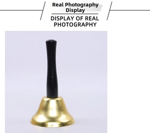 Detail of classic gold metal hand bell featuring a long black wooden handle for service