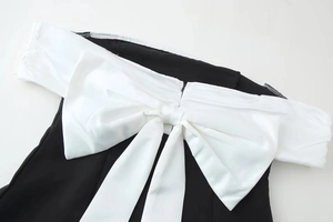 Detail of contrast black and white off-shoulder top featuring a large satin bow accent