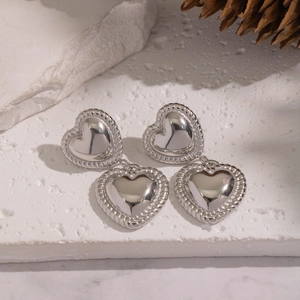 Detail view of heart drop earrings with textured rope edges on white stone surface