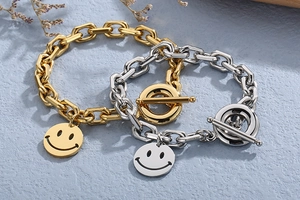 Close-up of gold and silver chunky chain bracelets with smiley face pendants and OT toggles