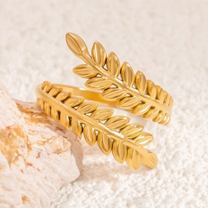 Adjustable golden leaf open ring in stainless steel displayed on coral stone
