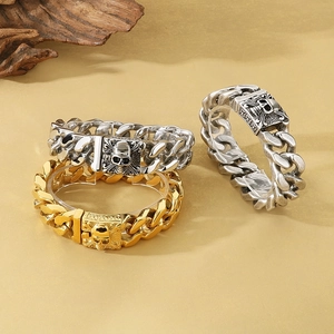 Detail of punk style skull clasp Cuban chain bracelets in gold, silver, and antique silver